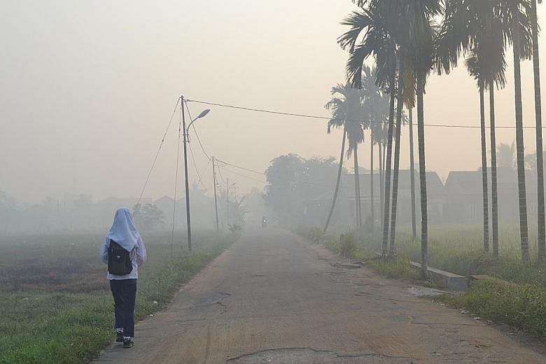 A student walking along a road amid thick haze in Pontianak, in the Indonesian province of West Kalimantan, on Monday.