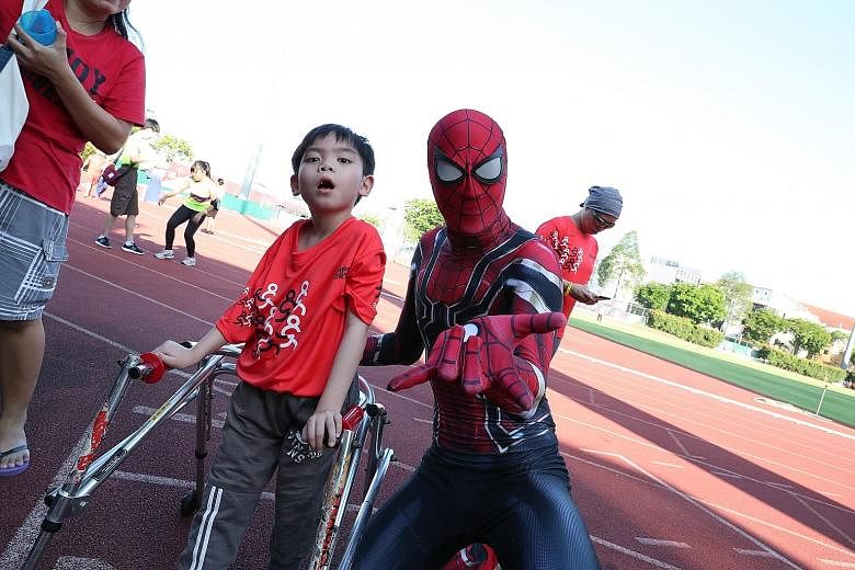 Poo Jia Ming, eight, from the Cerebral Palsy Alliance Singapore School, with "Spider-Man" Neyton Tan, taking part in this year's Run For Inclusion, where athletes with disabilities run alongside the able-bodied.