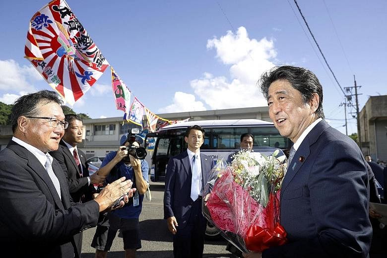 Japanese Prime Minister Shinzo Abe receiving a bouquet after announcing his candidacy for the ruling Liberal Democratic Party leadership election in Tarumizu, Kagoshima prefecture, yesterday. Mr Abe, who took office in December 2012, will be on track
