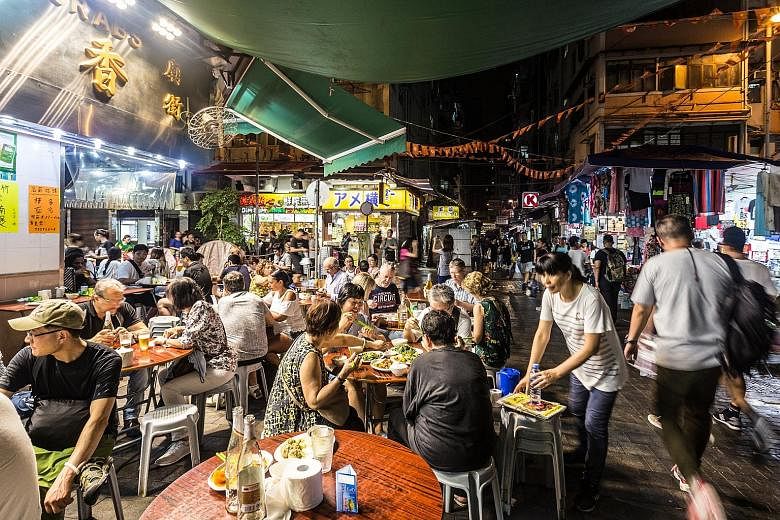 Tourists and locals dining at a street near the famous Temple Street Night Market in Hong Kong.