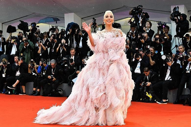 After playing a girl-next-door in A Star Is Born, Lady Gaga reverted to her flamboyant self, wearing a dress made of long pink feathers at the film's world premiere at the Venice Film Festival.