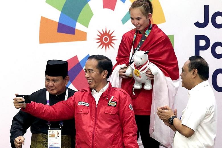 Indonesian President Joko Widodo and Indonesian Pencak Silat Association chairman Prabowo Subianto (far left) with Indonesian gold medallist Wewey Wita at the awards ceremony for the women's 50kg to 55kg Padepokan Pencak Silat event at the Asian Game