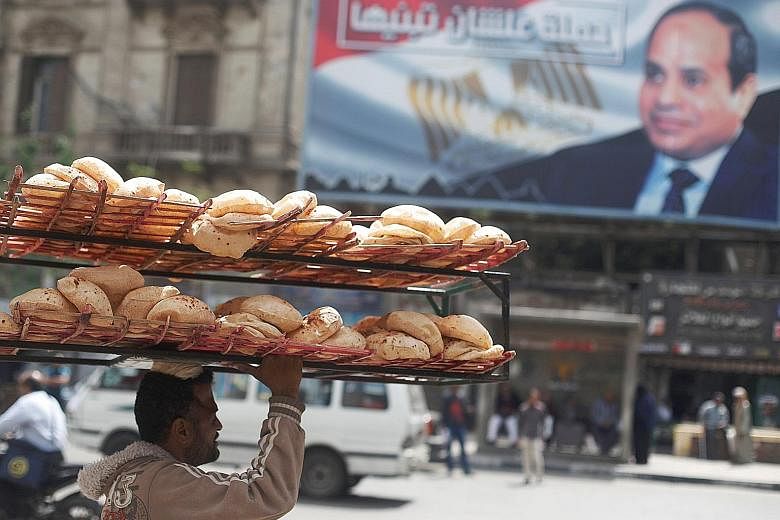 A bread seller walking past a banner featuring President Abdel Fattah el-Sisi. Egypt has seen a significant hike in inflation and a decline in purchasing power and living standards.
