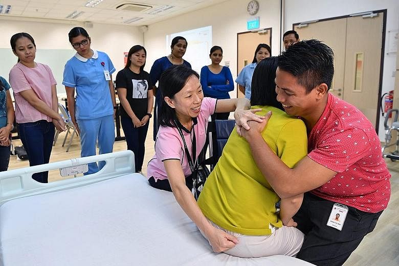 Principal physiotherapist Margaret Goh guiding a trainee on shifting a person from bed to wheelchair at the Community Training Institute.