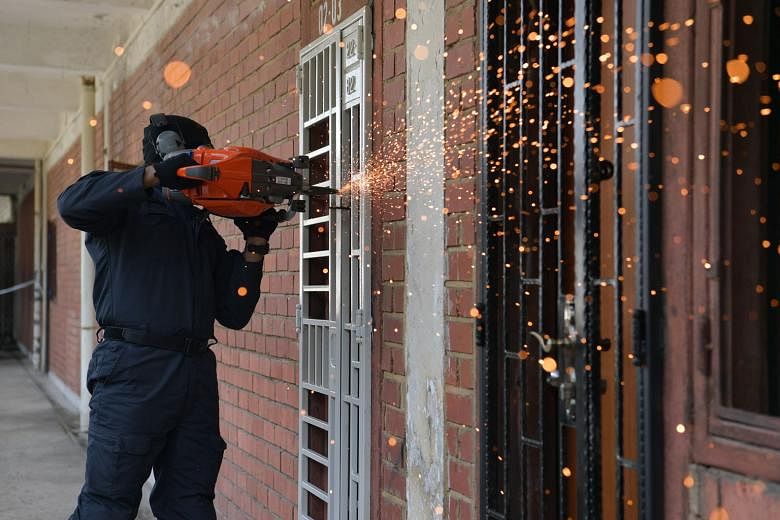 A Special Task Force officer demonstrating how to gain quick entry into a suspected trafficker's hideout using a motorised saw to cut open gates.