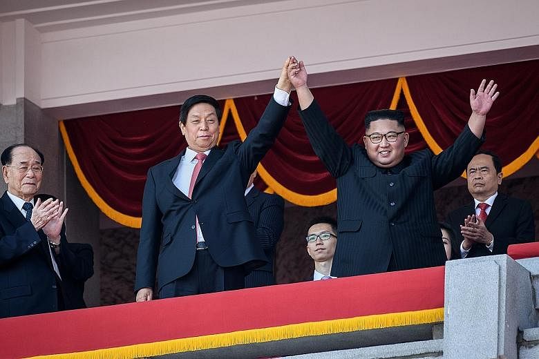 North Korean leader Kim Jong Un (right) acknowledging the crowd with Mr Li Zhanshu, a member of the Chinese Communist Party's Politburo Standing Committee, who was in Pyongyang as President Xi Jinping's envoy. Tanks and artillery were on display at t