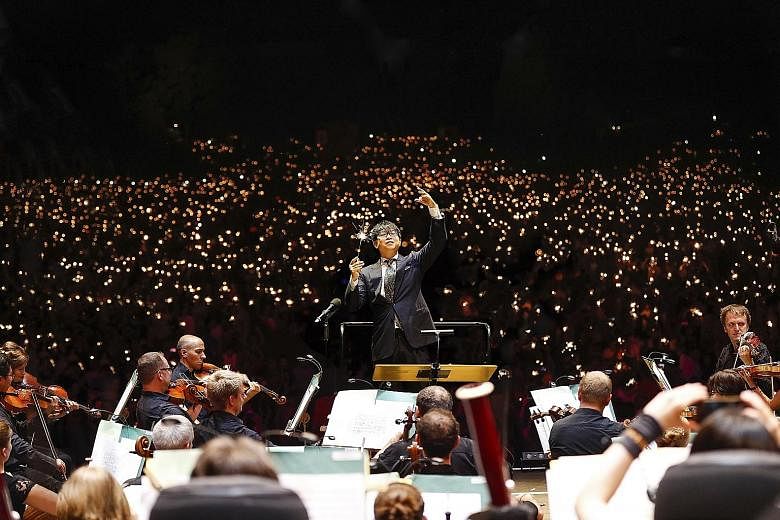 Mr Wong Kah Chun conducting the Nuremberg Symphony Orchestra during the Klassik Open Air concert that attracted 65,000 people. Instead of a baton, he is holding a sparkler like the audience as night falls over the park.