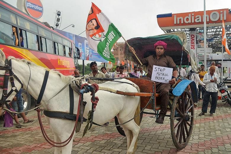 A Congress party activist holding a party flag and placard while sitting on a cart next to a petrol station in Ajmer yesterday during a nationwide strike called by the main opposition parties. The opposition is looking to tap public anger against Pri