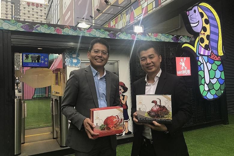 VeriTAG chief executive Jason Lim (left) at the firm's first unmanned minimart in Chengdu, which showcases food from up to 20 Singapore brands, including frozen crab dishes from House of Seafood. With him is the Singapore restaurant chain's chief exe