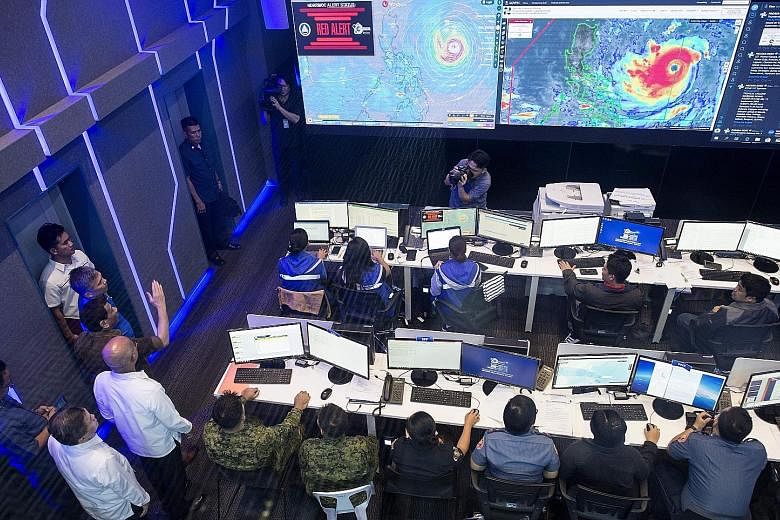 Philippine President Rodrigo Duterte (left, with arm raised) visiting the National Disaster Risk Reduction and Management Council operations centre in Manila yesterday, as Typhoon Mangkhut barrelled towards the country. Schools were shuttered and som