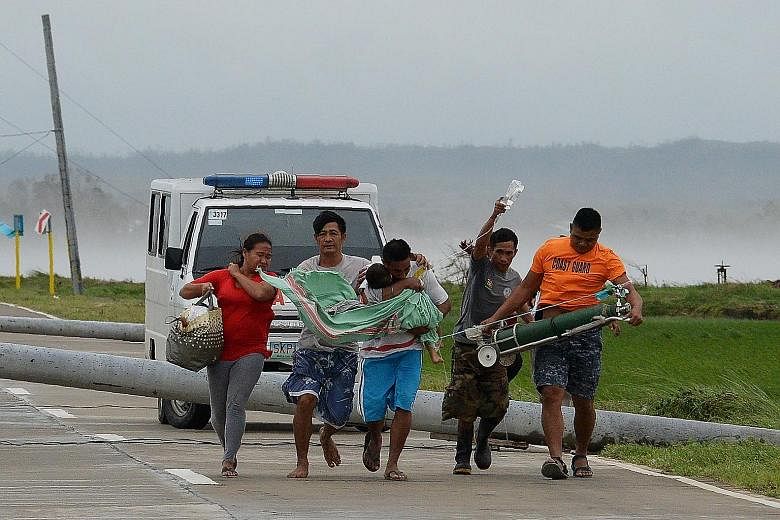 A father carrying his sick child to another car after their ambulance could not get past electric posts toppled by strong winds after Super Typhoon Mangkhut hit Baggao town in the Philippines yesterday.