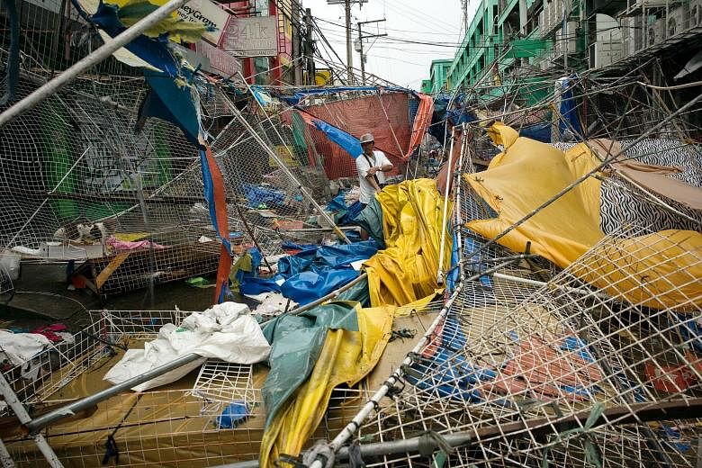 Above: Wreckage at a bazaar after Super Typhoon Mangkhut hit Tuguegarao, Cagayan province, in the Philippines yesterday. Left: Heavy rain and strong winds lashed Manila.