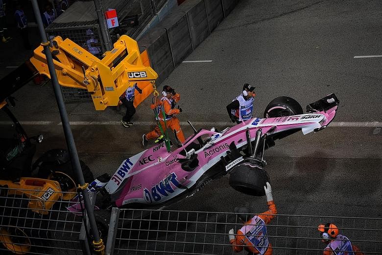 A downcast Sebastian Vettel walking past the Mercedes of Singapore Grand Prix winner Lewis Hamilton, after finishing third in the race to fall further behind the Briton in the drivers' championship. Esteban Ocon's car being removed from the track, af