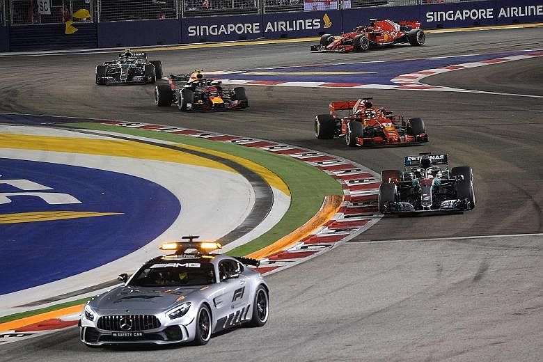A downcast Sebastian Vettel walking past the Mercedes of Singapore Grand Prix winner Lewis Hamilton, after finishing third in the race to fall further behind the Briton in the drivers' championship. Esteban Ocon's car being removed from the track, af
