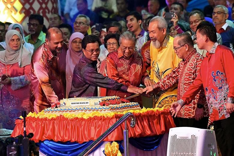 Malaysian Prime Minister Mahathir Mohamad, flanked by Sabah Governor Juhar Mahiruddin (in yellow) and Sabah Chief Minister Mohamad Shafie Apdal, cutting a cake with Sarawak Deputy Chief Minister Amar Douglas Uggah Embas (red batik) during the Malaysia Day