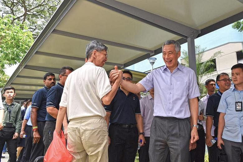 Prime Minister Lee Hsien Loong greeting a passer-by near Little India MRT station yesterday. A 150m linkway connecting the station to Tekka Market is the latest covered walkway finished under LTA's Walk2Ride scheme.