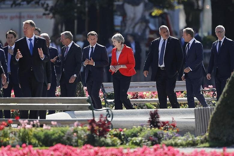 British Prime Minister Theresa May and French President Emmanuel Macron conversing as they and other European Union leaders take a time-out at their summit in Salzburg, Austria, yesterday.