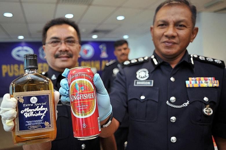 Shah Alam District Police chief Baharudin Mat Taib (right) and his deputy, Superintendent Nek Zaidi Zakaria, with two types of the illegal alcoholic drinks seized in raids in Selangor.