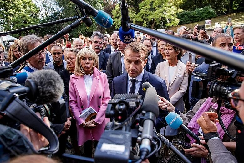 French President Emmanuel Macron speaking to the press as his wife, Brigitte, looks on during a visit to Bougival, near Paris, earlier this month. Mr Macron's approval rating has plunged to only 19 per cent, with 60 per cent finding his achievements 