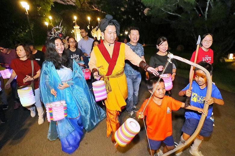 Performers dressed up as Chinese folklore characters Chang Er and Hou Yi leading Ryan Dinzly Naiman (in orange top), nine, Syahfril Hans (in blue top), 10, and other beneficiaries of the President's Challenge for a tour of the Istana grounds yesterda