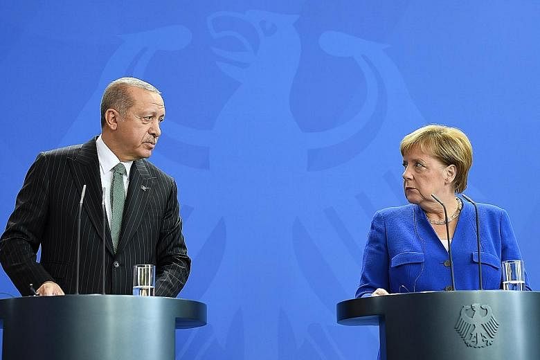 Turkish President Recep Tayyip Erdogan and German Chancellor Angela Merkel speaking at a news conference in Germany yesterday. Mr Erdogan is on a state visit to patch bilateral ties, but rights campaigners and German politicians are angered by the re