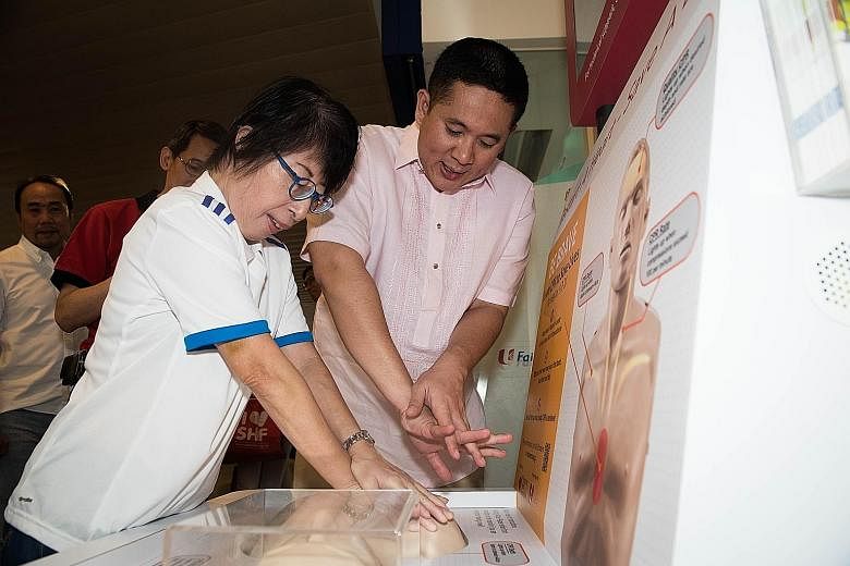 Senior Parliamentary Secretary for Health and Home Affairs Amrin Amin (left) helping a member of the public try out the new CPR kiosk (above) at Toa Payoh HDB Hub.