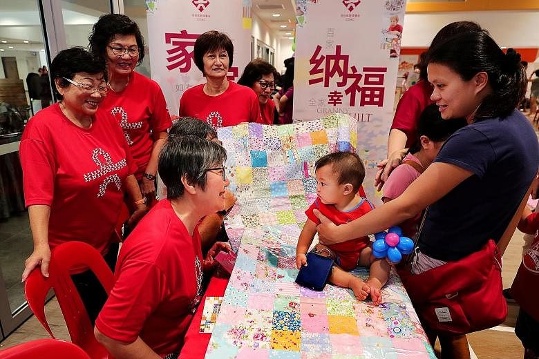 Housewife Amy Loh (right), 35, with her seven-month-old baby, Ajay Tan, at the booth of the Granny Quilt Project at Radin Mas Community Club yesterday. The Chinese Development Assistance Council (CDAC) piloted the Granny Quilt Project in August last 