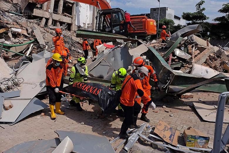 Indonesian rescuers removing the body of a quake victim in Palu, in Central Sulawesi, yesterday following last Friday's temblor. Officials said more than 61,000 people have been displaced across the disaster-hit areas.