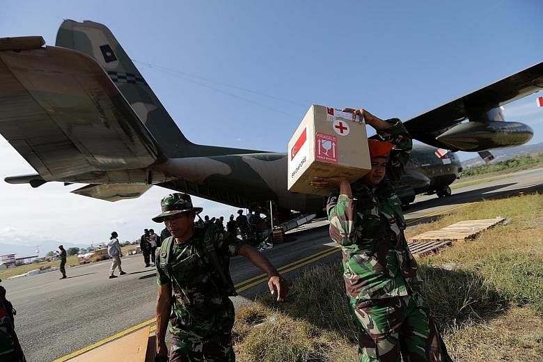 Indonesian military personnel unloading supplies from a Singapore military plane at Mutiara Al Jufri Airport in Palu yesterday. Ms Susi Rahmatia in an emotional reunion with her five-year-old son Jumadil yesterday, after he went missing for seven day