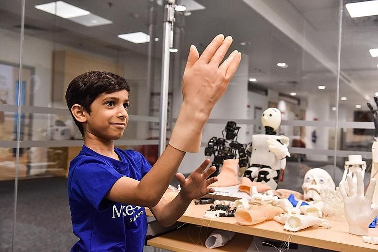 Zahaan Tambawala meeting Poppy, a customised robot, yesterday. He also tried on artificial skin (right) designed for robots. The aspiring "robot builder", who had been battling cancer, celebrated his one-year anniversary of defeating the disease with
