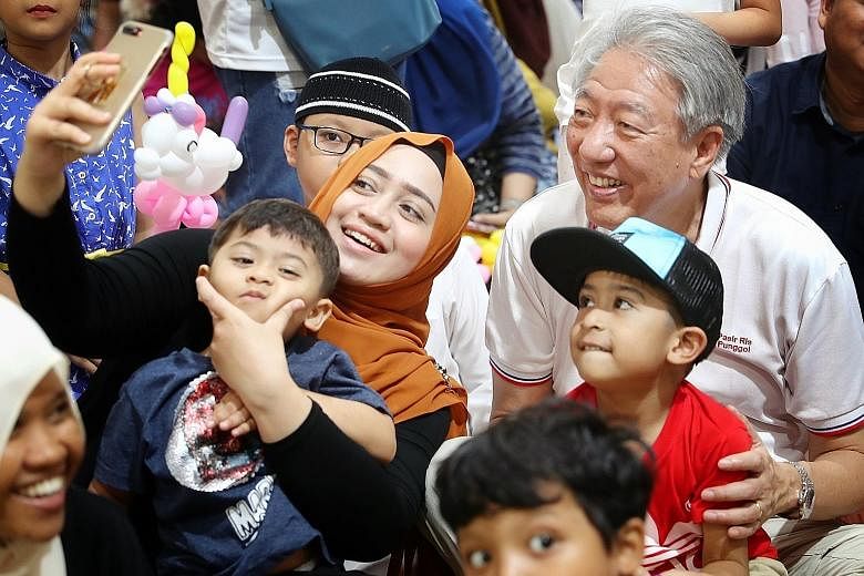 Deputy Prime Minister Teo Chee Hean having his picture taken with a family at the Malay Cultural Village event yesterday.