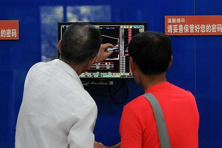 Investors monitoring stock prices in Jiujiang, Jiangxi province, yesterday. Foreigners yesterday dumped 9.7 billion yuan (S$1.96 billion) of A shares through exchange links with Hong Kong.