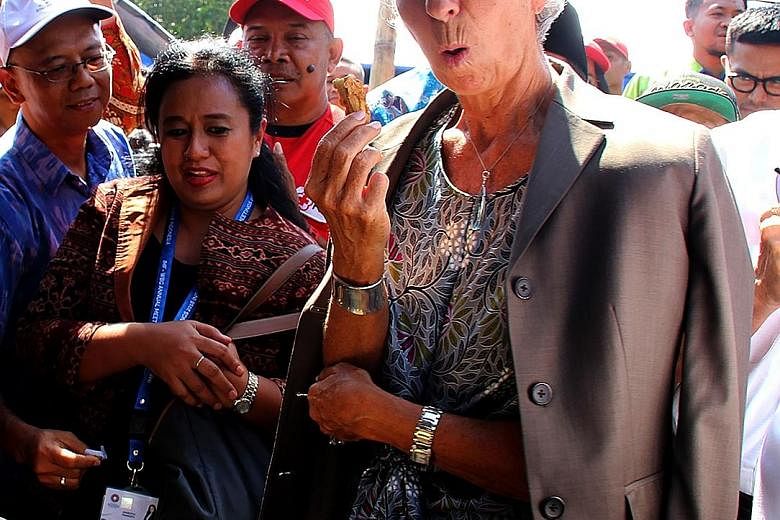 IMF chief Christine Lagarde sampling fried banana on a visit to Gunung Sari on Lombok Island on Monday. Supporters of presidential hopeful Prabowo Subianto have said the government was insensitive in going ahead with the meetings in the aftermath of 