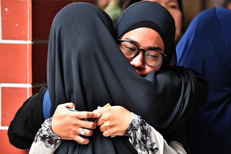Above: 3WO Muhammad Sadikin Hasban's wife Norsidah Kamilan (facing camera) being comforted during the funeral. Left: The body of 3WO Sadikin being transferred to the burial site at Lim Chu Kang Muslim Cemetery yesterday.