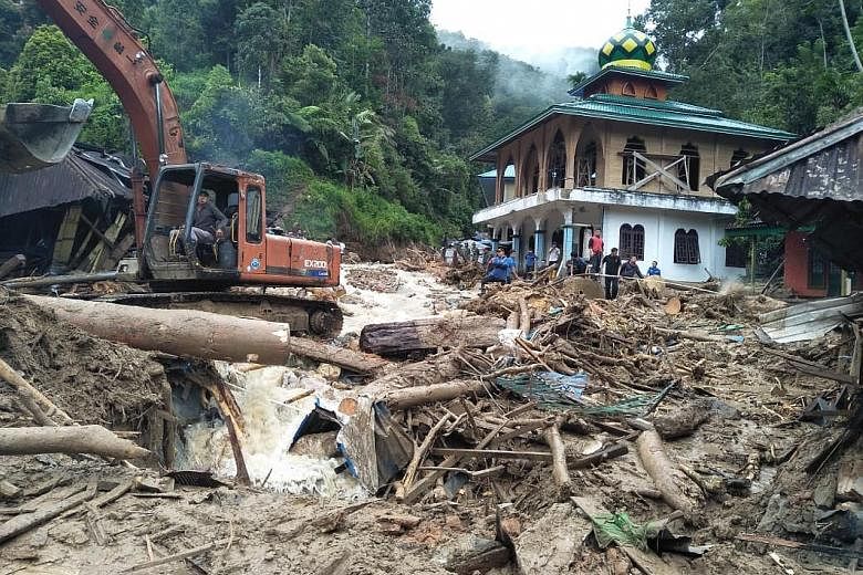 Rescue workers removing debris after flash floods hit Muara Saladi village in Mandailing Natal yesterday. Eleven students died after being swept away when a landslide smashed into their school.