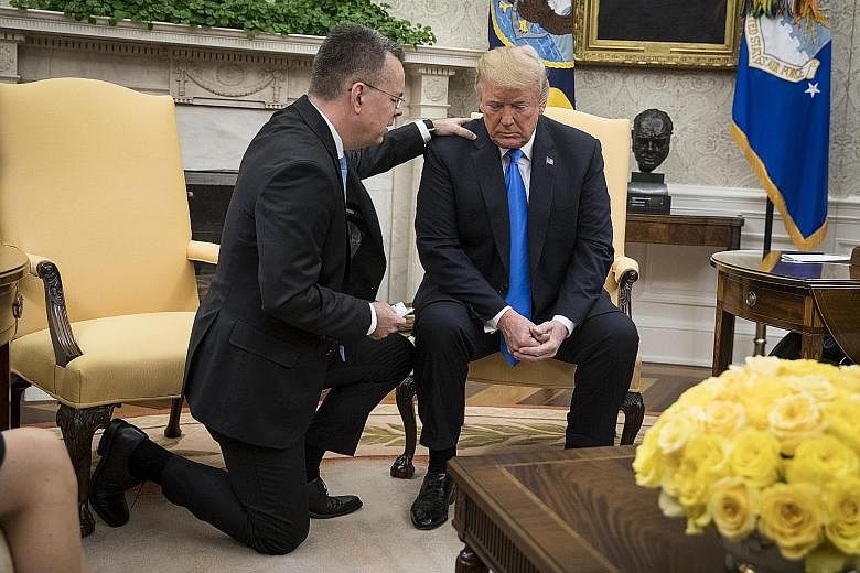 Pastor Andrew Brunson praying with President Donald Trump in the Oval Office in Washington on Saturday. His release after two years in detention came as the Turkish government was seeking help from Mr Trump in its dispute with Saudi Arabia over the d