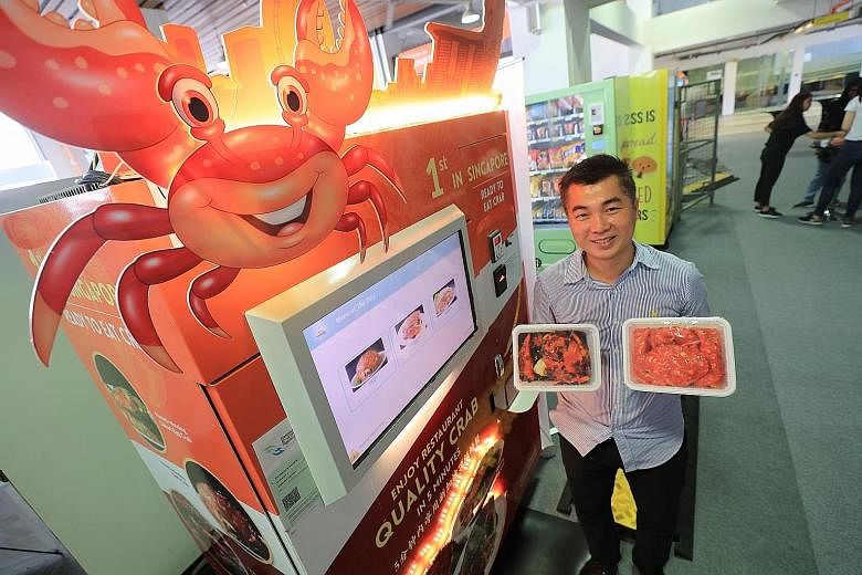 Above: House of Seafood CEO Francis Ng showing off a vending machine which dispenses chilli crab, black pepper crab and salted egg crab dishes. Top: A machine with palm-recognition technology that collects payment from a customer's e-wallet before di