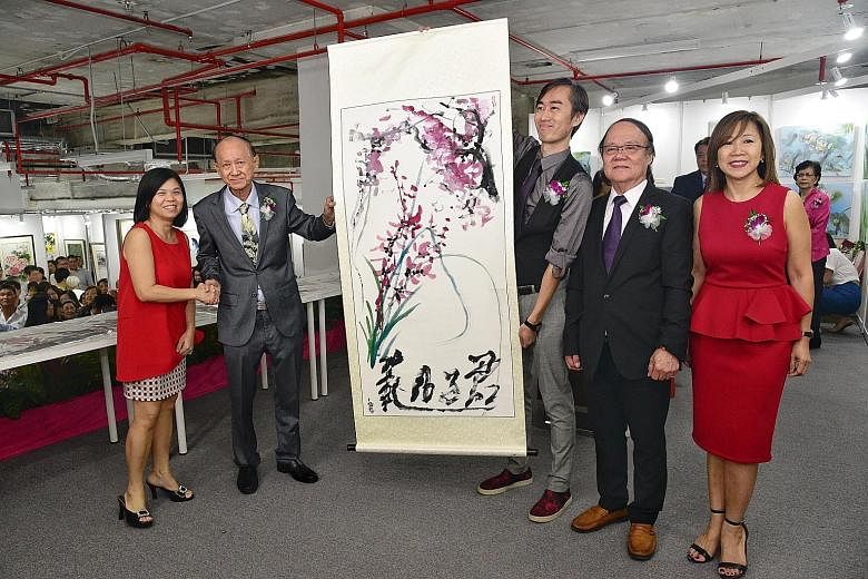 Artist and art educator Tan Khim Ser painting Graceful Abundance, which is on display at the Life Art Society exhibition at Wisma Atria. The painting is priced at $20,000. From left: Ms Tan Bee Heong, general manager of The Straits Times School Pocke