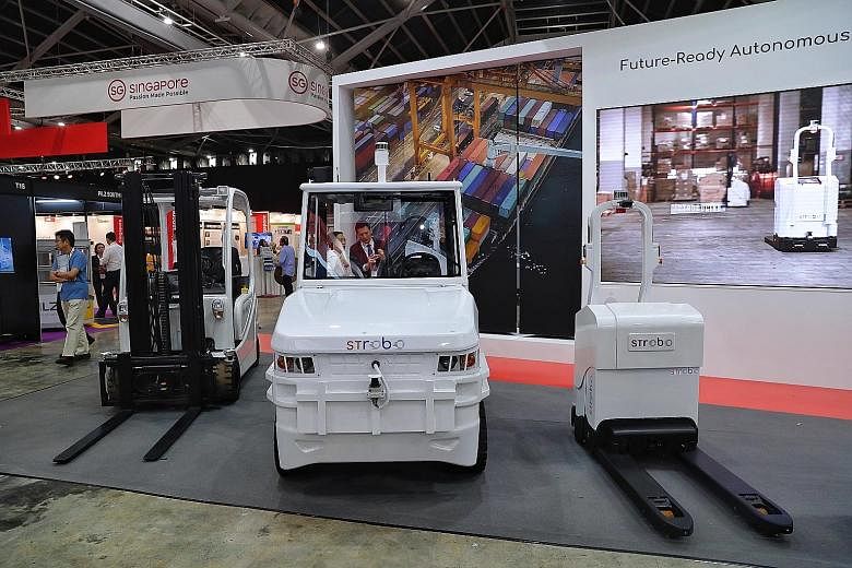 Above: ST Engineering's range of STrobo robots includes (from left) an autonomous forklift, an autonomous tow tractor and an autonomous pallet truck. Above left: The autonomous pallet stacker demonstrating its capabilities yesterday at the Industrial