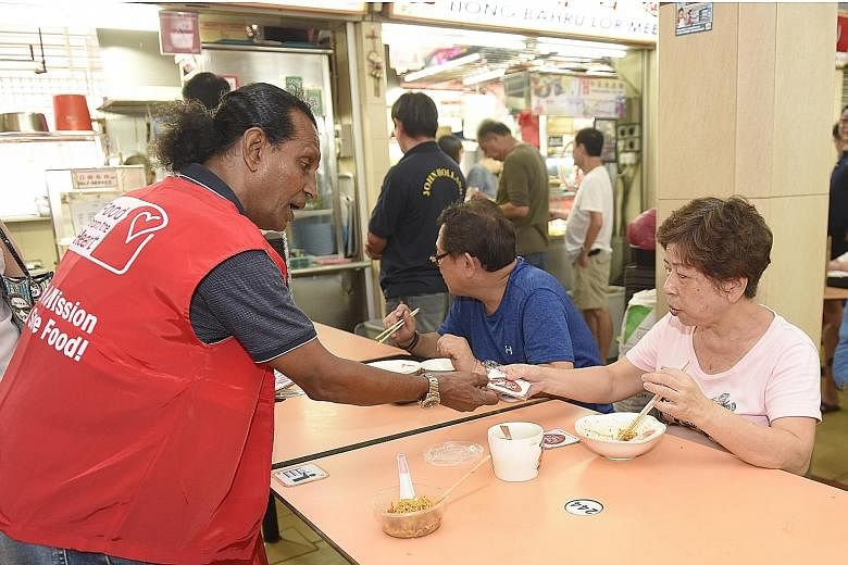 Above: Mr Muhd Jason Maharaj, 62, a volunteer with Food from the Heart, giving out campaign coasters to patrons at Old Airport Road Food Centre. Left: Mountbatten MP Lim Biow Chuan pasting the Clean Plate Campaign decal on a stall.