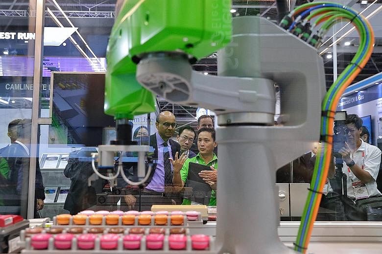 Deputy Prime Minister Tharman Shanmugaratnam observing an automated macaron-making machine during his tour of the Industrial Transformation Asia-Pacific trade show yesterday. (From left) Moderator Christoph Schmitz, Minister for Trade and Industry Ch
