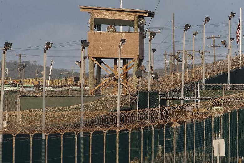 Above: A watch tower at Camp Delta at the US military-run detention centre in Guantanamo Bay, Cuba. Left: Detainees performing their morning prayers at the prison. Guantanamo has not received any new inmates since 2008, and 40 remain.