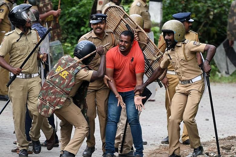 Indian police detaining an activist as protesters rallied against a Supreme Court verdict revoking a ban on the entry of women of menstrual age to a Hindu temple in the state of Kerala yesterday.