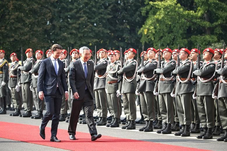 Austrian Chancellor Sebastian Kurz accompanying Prime Minister Lee Hsien Loong as he is welcomed by a military honour guard at the Federal Chancellery in Vienna yesterday. Both countries inked a pact to step up cooperation in digitalisation and infor