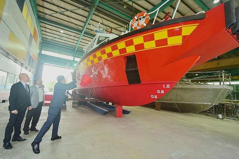 SCDF Commissioner Eric Yap launching the White Swordfish on Wednesday by splashing a bucket of sea water onto the bow. To be deployed at the upcoming Punggol marine outpost, the new vessel is the SCDF's third purpose-built Rapid Response Fire Vessel.