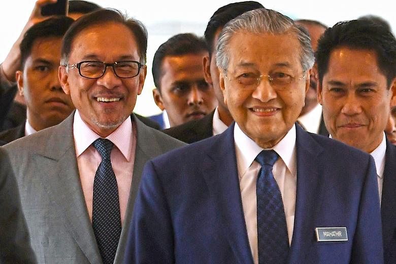 Prime Minister Mahathir Mohamad (front) and Port Dickson MP Anwar Ibrahim arriving in Parliament yesterday, where the premier presented the mid-term review of Malaysia's five-year economic blueprint.