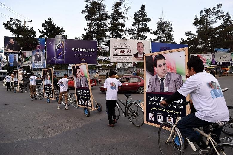 Supporters of candidate Alhaj Amir Gull Shaheen riding bicycles with a campaign trailer along a street in Kabul on Monday.