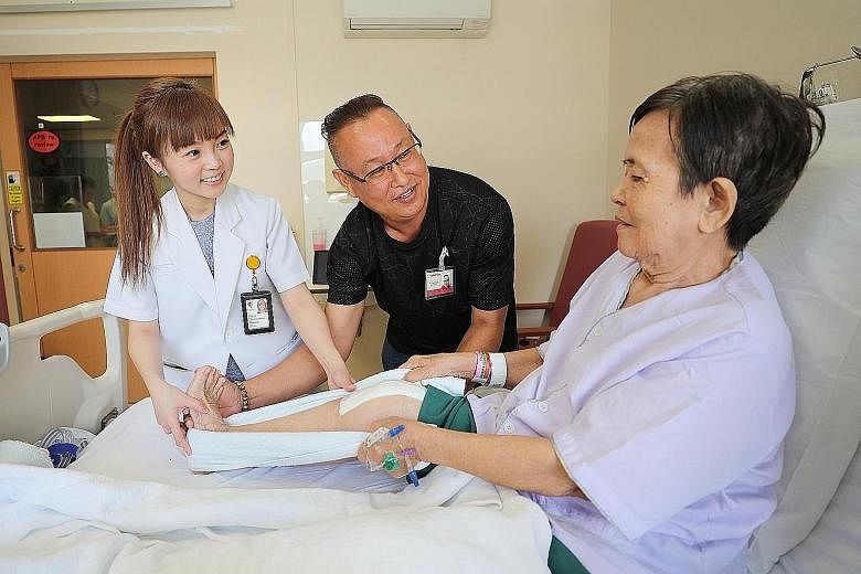 Part-time handyman Lim Thiam Beng and senior physiotherapist Jaclyn Tan giving exercise tips to a knee replacement surgery patient who wanted to be known only as Madam Chong.