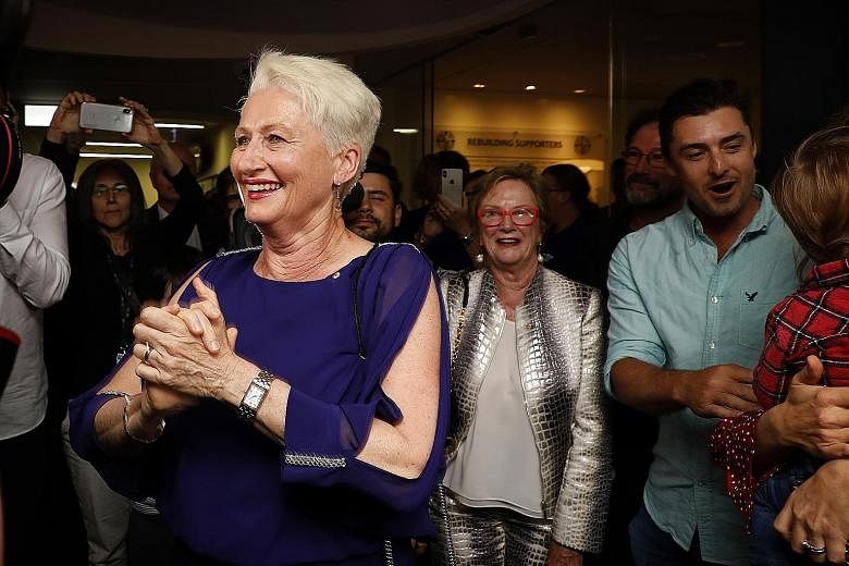 Independent candidate for Wentworth Kerryn Phelps (front) being congratulated by supporters as she arrives for a Wentworth by-election evening function at North Bondi Life Saving Club, Sydney, yesterday. With 54 per cent of the vote counted last nigh