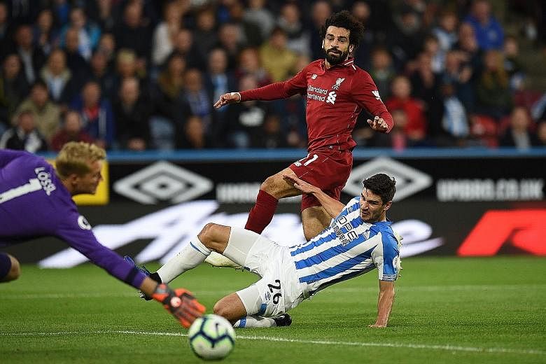 Liverpool's Mohamed Salah (in red) shooting past Huddersfield's Christopher Schindler and goalkeeper Jonas Lossl for the only goal in the Reds' 1-0 win.